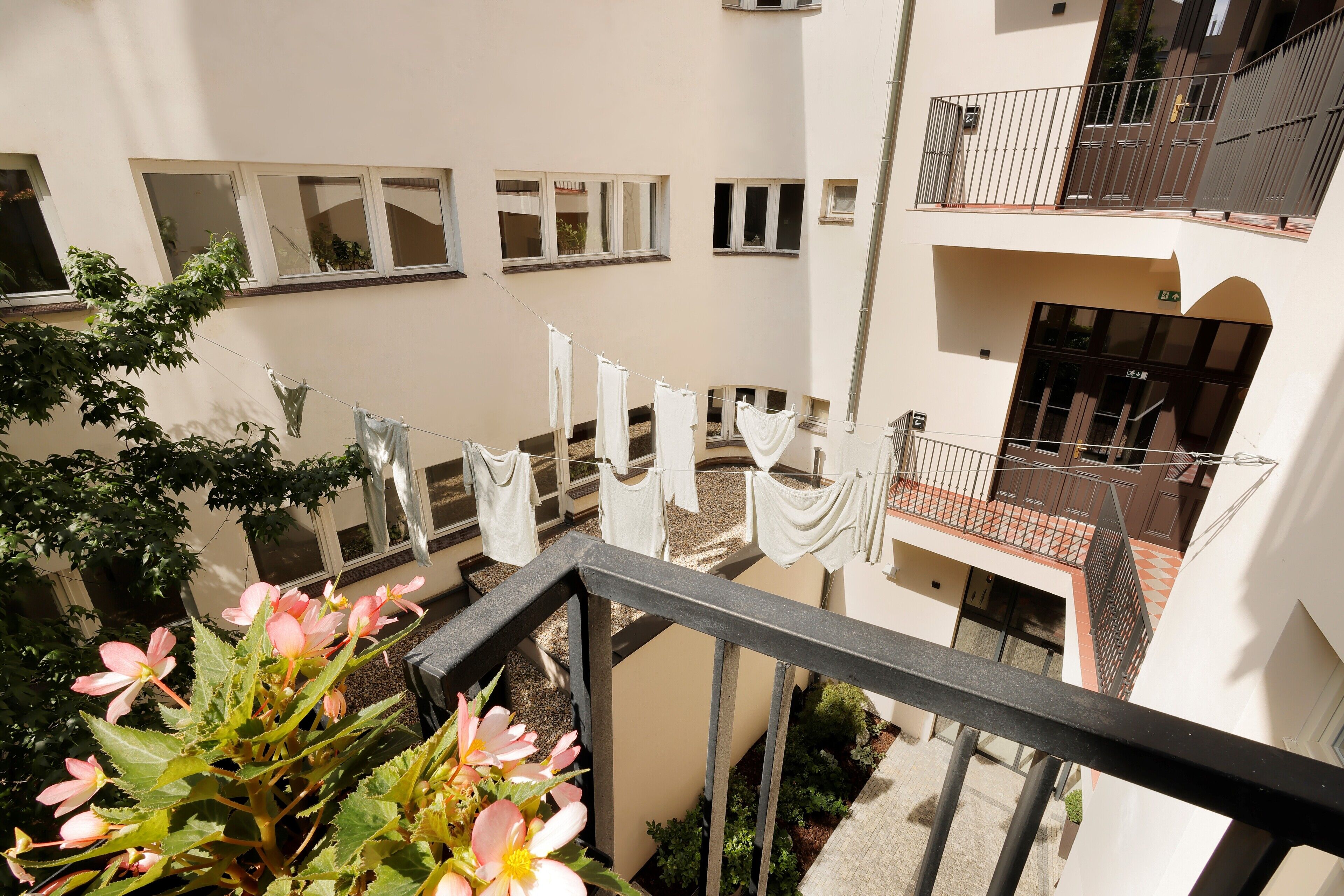 Un edificio residencial de varios niveles con balcones, ventanas y un jardín con flores.