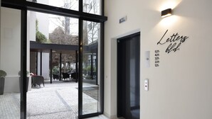 Une entrée moderne avec une porte en verre, un panneau mural indiquant les niveaux des étages et une enseigne indiquant « Bâtiment des services postaux ».