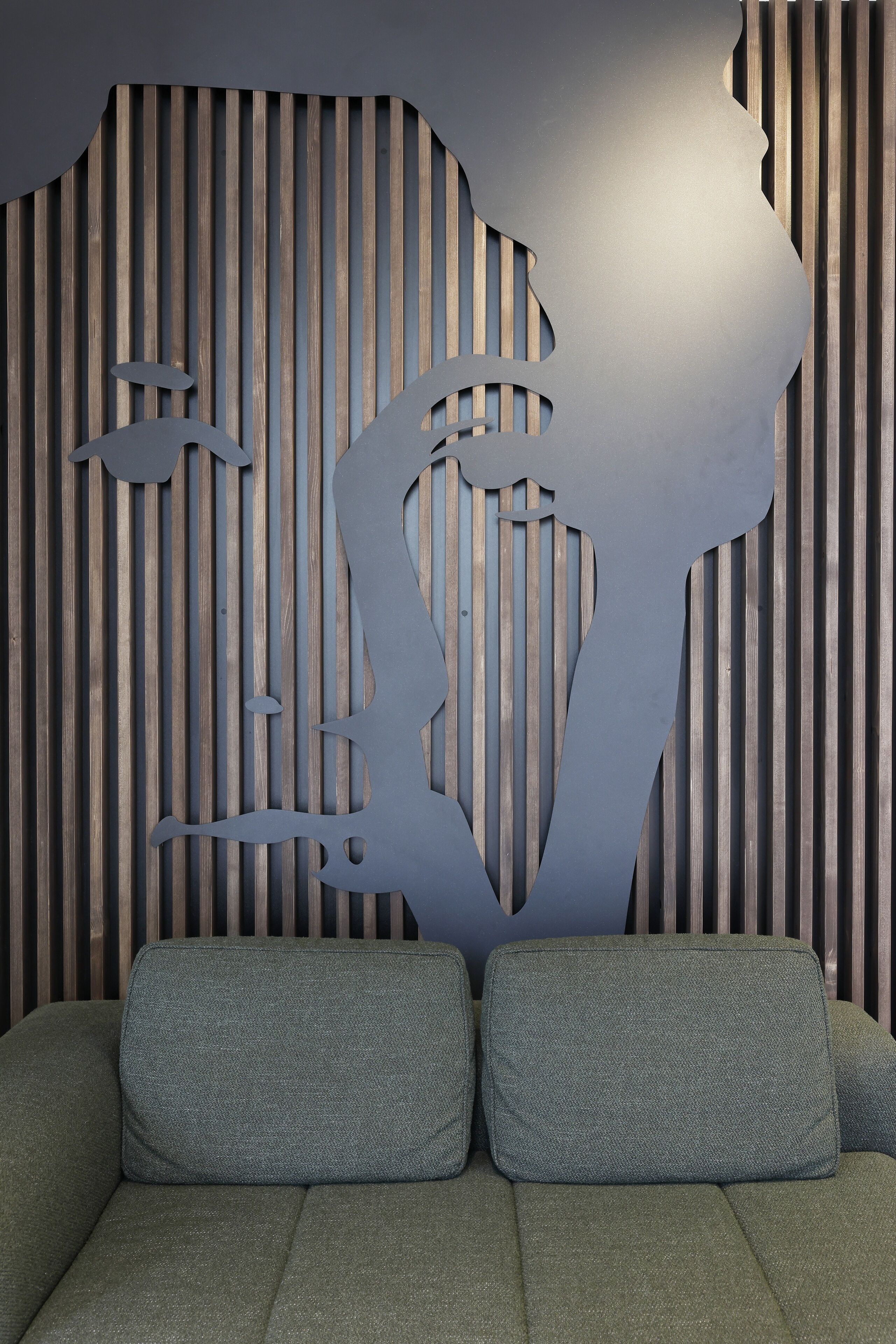 A modern interior with a sofa and a wall with vertical wooden slats.