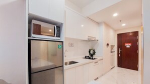 A compact kitchen with a refrigerator, microwave, and sink. - Fully Furnished And Modern 2Br Apartment At Sky House Bsd (Pagedangan)
