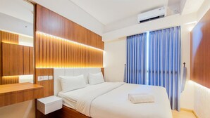 A modern hotel room with a wooden headboard, a large bed with white linens, a bedside table, and a window with blue curtains. - Fully Furnished And Modern 2Br Apartment At Sky House Bsd (Pagedangan)