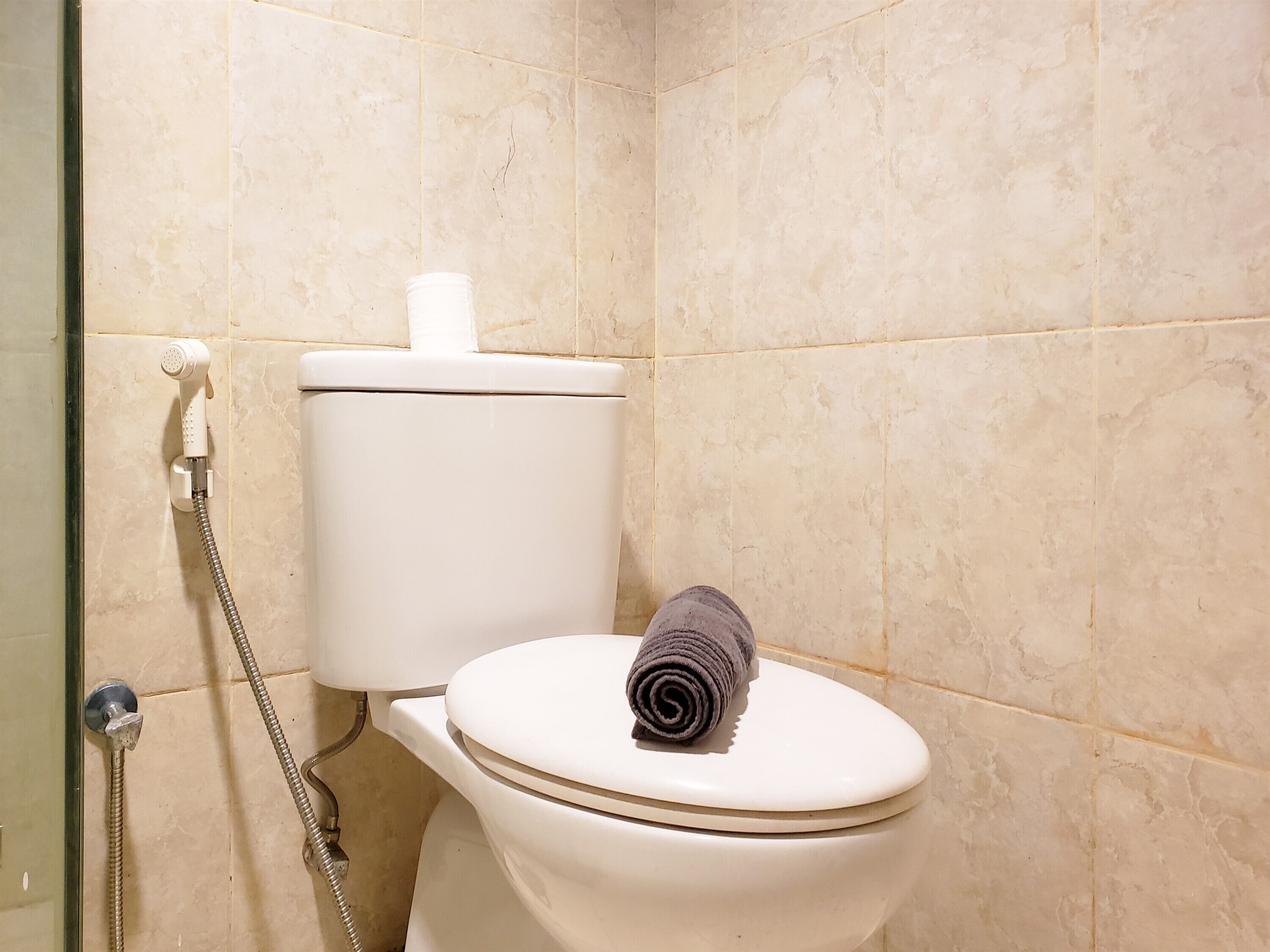 Une salle de bain avec des toilettes, une douche et une serviette posée sur la lunette des toilettes.