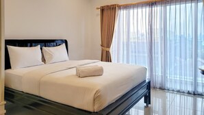 A hotel room with a bed, a window with sheer curtains, and a view of buildings outside. - Fancy And Nice Studio At Tamansari The Hive Apartment (Jakarta)