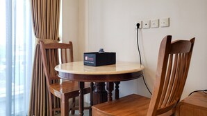 A round wooden table with a black box labeled "travelio" and a power outlet on the wall. - Fancy And Nice Studio At Tamansari The Hive Apartment (Jakarta)