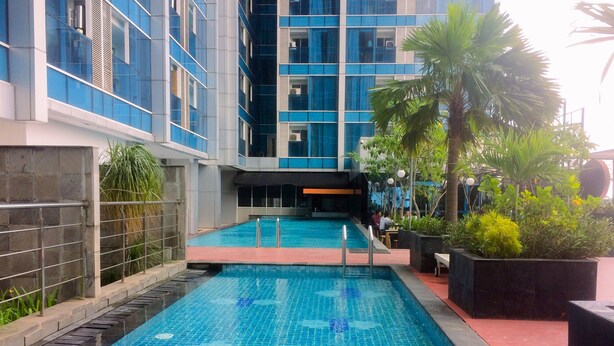 A modern indoor swimming pool with clear blue water, surrounded by a stone wall and a metal railing. - Fancy And Nice Studio At Tamansari The Hive Apartment (Jakarta)