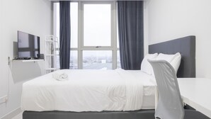 A hotel room with a bed, a TV, a desk, and a chair.
