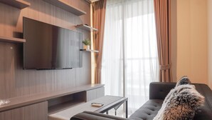 Una sala de estar moderna con un televisor de pantalla plana en la pared, un sofá, una mesa de centro y una planta en maceta.