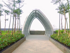 Un sendero arqueado que conduce a un edificio, rodeado de follaje y árboles.