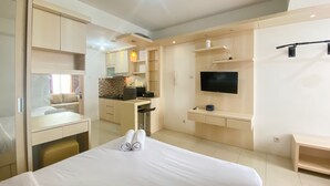 Ein Hotelzimmer mit einem Bett, einem Schreibtisch, einem Fernseher und einer Küchenzeile.
