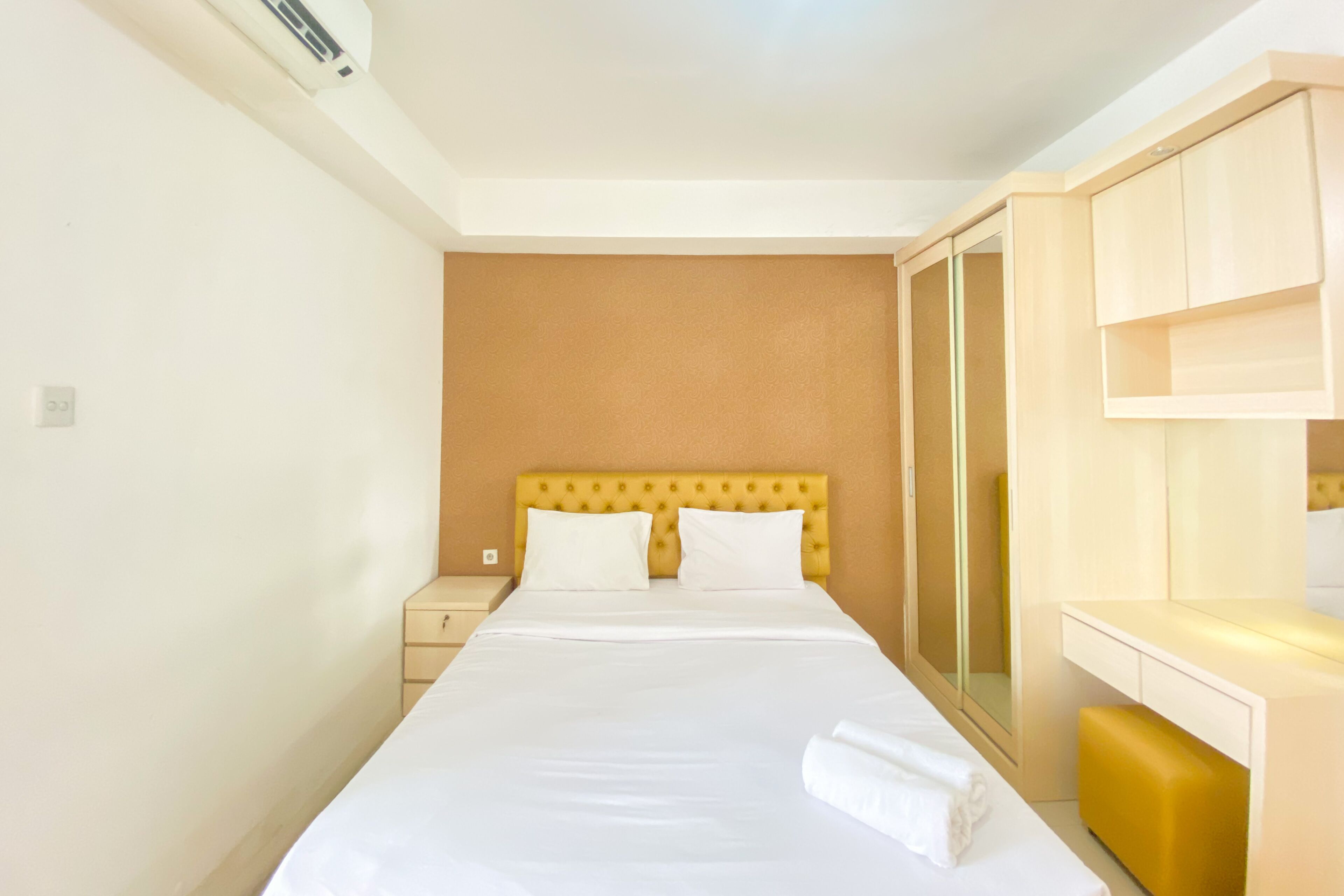 A neatly made bed with white linens, a wooden headboard, and a bedside table with a lamp.
