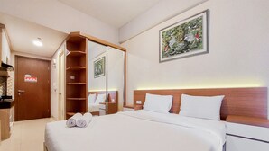 Una habitación de hotel con una cama grande, un armario de madera, una mesita de noche y un cuadro enmarcado en la pared.