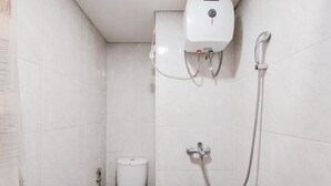 Un baño pequeño con azulejos, un inodoro, una ducha y un secador de manos.