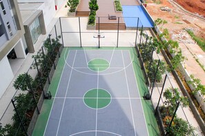 Enjoy a game of basketball on the outdoor court surrounded by lush greenery and modern architecture.