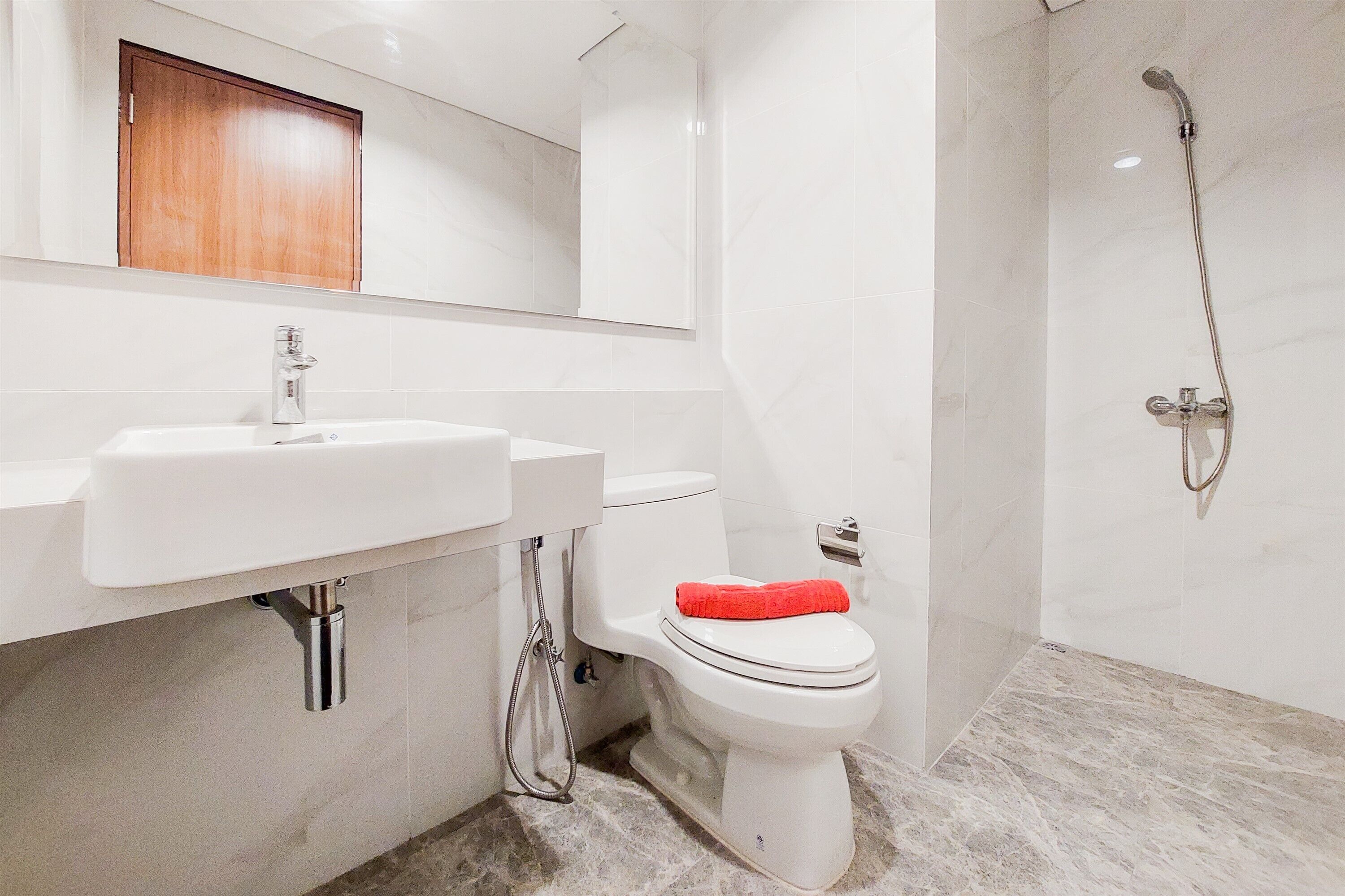 A modern bathroom with a white sink, toilet, and shower.