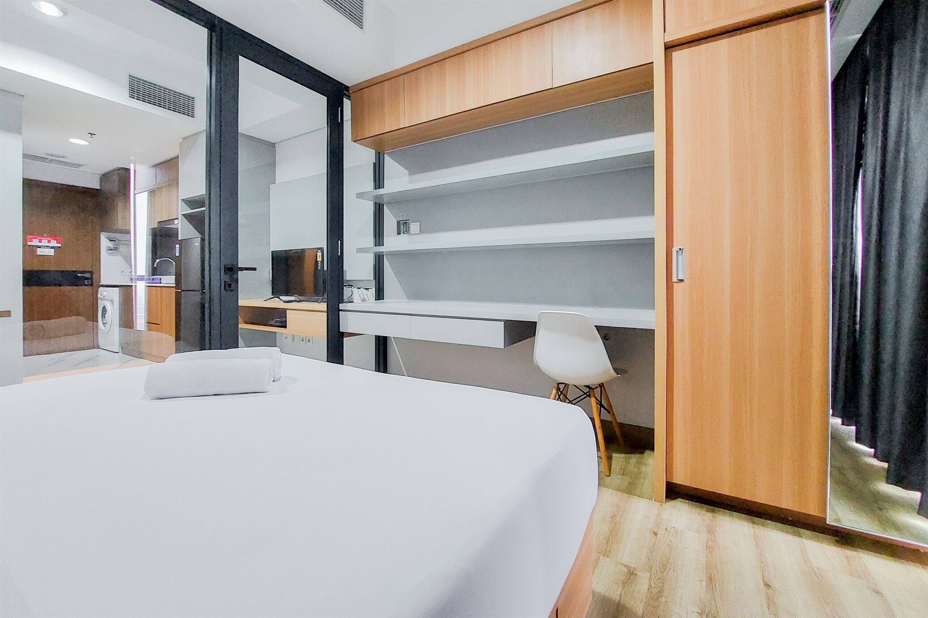 Una habitación de hotel con cama, escritorio, silla, armario y espejo.