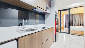 A modern kitchen with two sinks, a built-in oven, and a dining area with a sliding glass door to a balcony. - Gorgeous 1Br Apartment At The Smith Alam Sutera (Tangerang)
