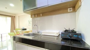 A modern kitchen with a black countertop, stainless steel sink, and a built-in microwave. - Homey And Cozy 2Br At Gateway Pasteur Apartment (Cimahi)