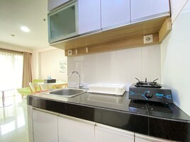Una cocina moderna con encimera negra, pileta de acero inoxidable y microondas integrado.