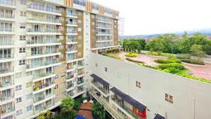 A multi-story residential building with balconies, a rooftop garden, and a view of a cityscape. - Homey And Cozy 2Br At Gateway Pasteur Apartment (Cimahi)