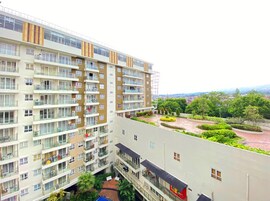 Un edificio residencial de varios pisos con balcones, un jardín en la azotea y vistas a la ciudad.