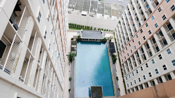 A high-rise building with a central swimming pool surrounded by balconies and greenery. - Homey 2Br At Puncak Bukit Golf Surabaya Apartment (Surabaya)