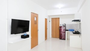 A modern kitchen with a built-in oven, a refrigerator, and a microwave. There is a flat-screen TV mounted on the wall. - Spacious And Best Deal 2Br Apartment At Puncak Bukit Golf Surabaya (Surabaya)