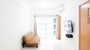 A bright, minimalistic room with a sofa, a flat-screen TV, and a large window with curtains. - Spacious And Best Deal 2Br Apartment At Puncak Bukit Golf Surabaya (Surabaya)