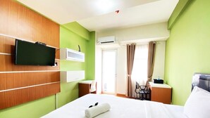 Une chambre d’hôtel avec un lit, un téléviseur fixé au mur, un bureau et une chaise.