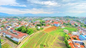 Une vue aérienne d’une ville comprenant des zones résidentielles, des champs agricoles et un bâtiment imposant situé au centre.