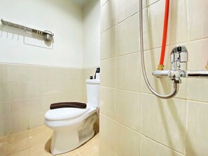 Casa de banho com sanita, chuveiro e um suporte para toalhas.
