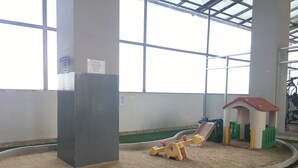 A children's play area with a sandpit, a small house, and a seesaw.