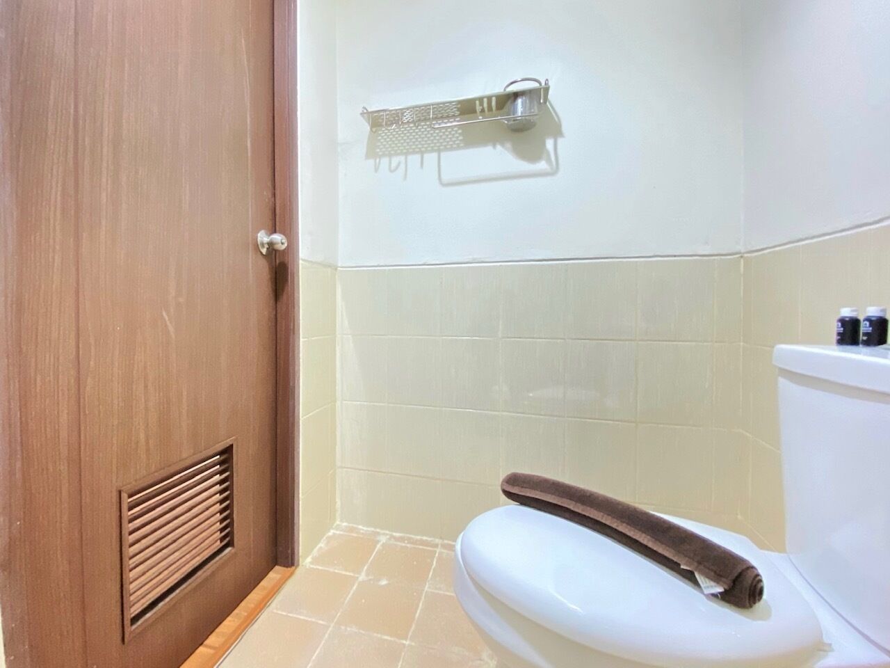 A bathroom with a toilet, a towel, and a shower curtain rod.