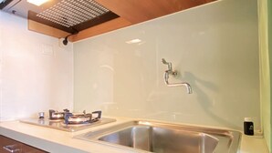 A kitchen with a stainless steel sink, wooden cabinets, and a modern light fixture.