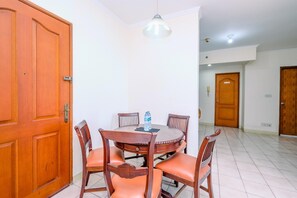 A dining area with a round table, six wooden chairs, a water bottle, and a pendant light.
