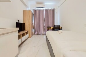 Ein Hotelzimmer mit Bett, Fernseher, Schreibtisch und Kleiderschrank.