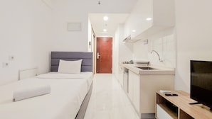 A modern hotel room with a single bed, a small kitchenette, and a television. - Great Deal And Comfortable Studio At Sky House Bsd Apartment (Pagedangan)