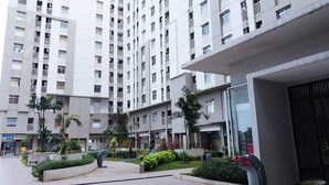 A modern apartment building with multiple balconies, a central courtyard with greenery, and a commercial space on the ground floor. - Cozy Living And Tidy 2Br Green Bay Pluit Apartment (Jakarta)