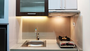 Una cocina compacta con un lavamanos de acero inoxidable, una estufa a gas y un horno empotrado.