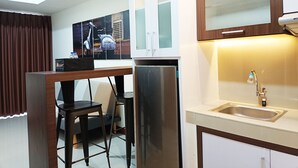 Una cocina moderna con un refrigerador de acero inoxidable, un lavamanos empotrado y un comedor con mesa y sillas.