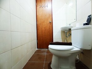 A bathroom with a toilet, sink, and wooden door. - Luxury 2Br At Vida View Makassar Apartment (Makassar)