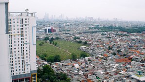 Un quartier urbain densément peuplé, composé d’un mélange de bâtiments résidentiels et d’un grand immeuble blanc de grande hauteur.