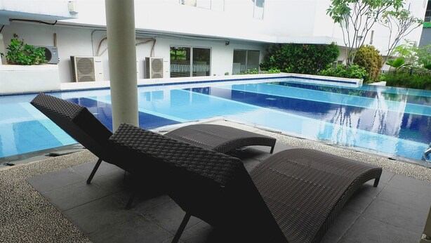 Une piscine avec des chaises longues et une terrasse carrelée.
