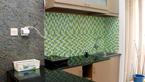 A kitchen with a checkered backsplash, a black countertop, and a sink. - Nice And Best Deal 2Br At Green Pramuka City Apartment (Jakarta)