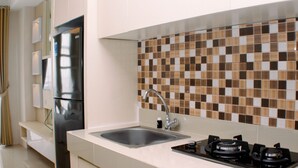 A modern kitchen with a stainless steel refrigerator, a sink, and a gas stove. - Luxurious Studio At Vasanta Innopark Apartment (Cikarang)