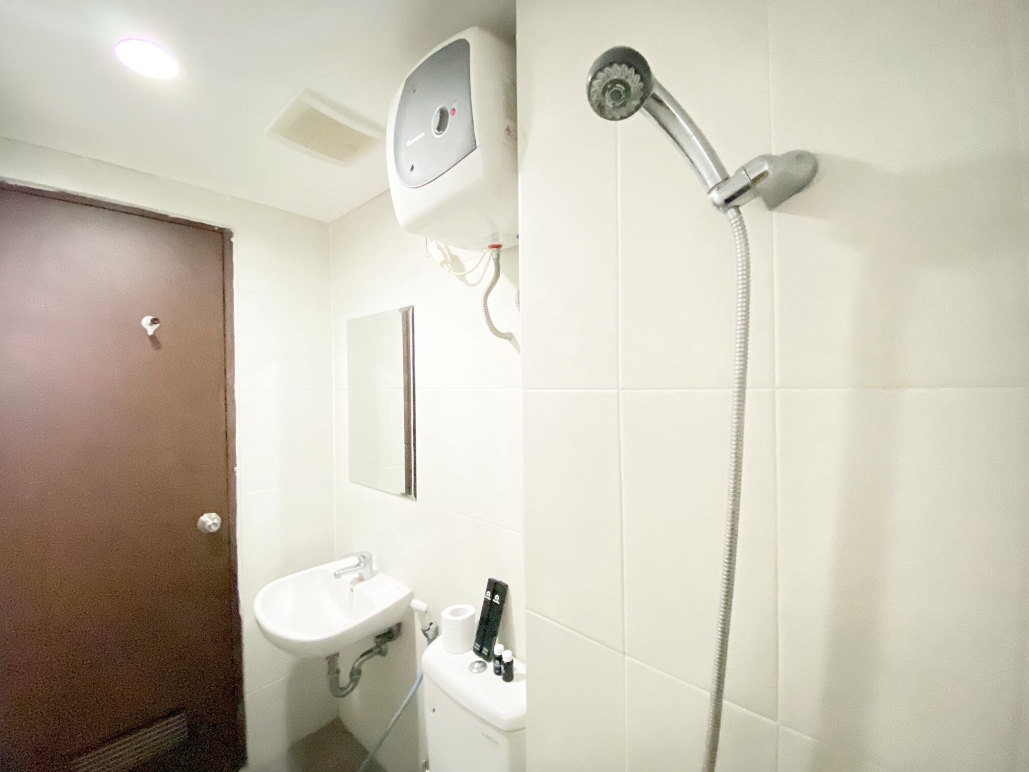 A bathroom with a shower, sink, toilet, and a mirror.