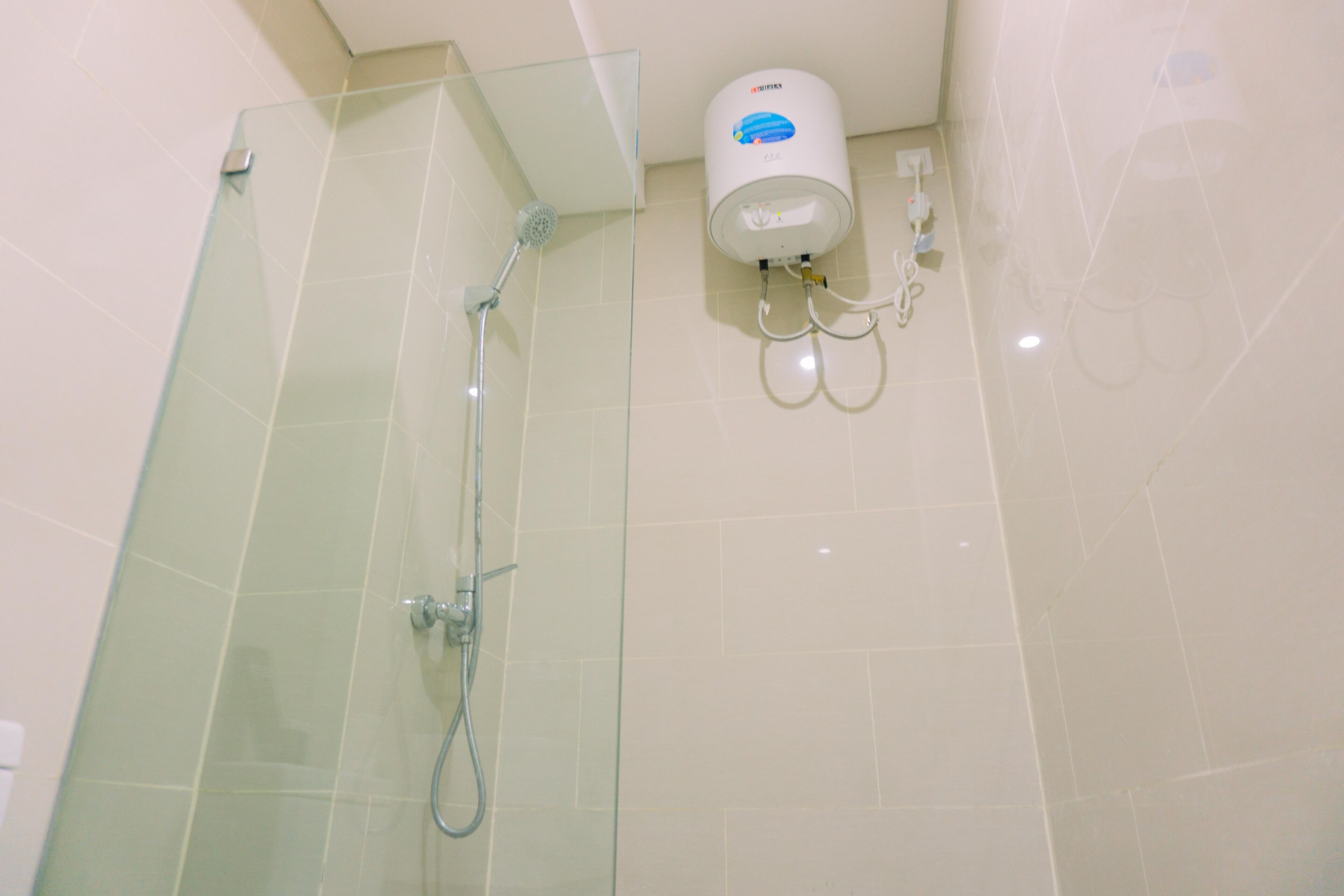 Uma casa de banho moderna com cabine de duche em vidro, chuveiro manual e humidificador de ar fixado na parede.