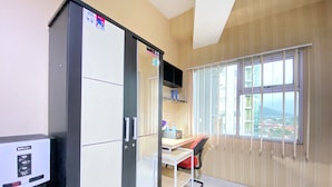 Une chambre compacte comprenant un coin cuisine, un bureau, une chaise et une fenêtre donnant sur la ville.