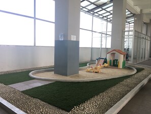 Children can play in the enclosed sandbox with a toy house and shovel.