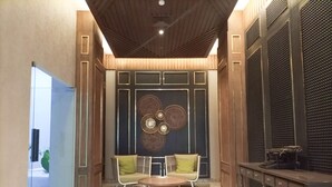 Un interior moderno con una zona de estar, una mesa redonda y un panel decorativo en la pared.