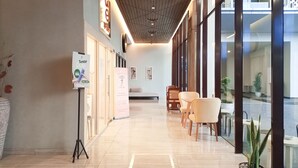 Un lobby moderno de hotel con piso pulido, zona de estar y ventanas amplias.